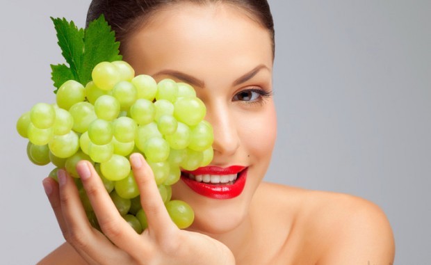 женщина с гроздью зеленого винограда