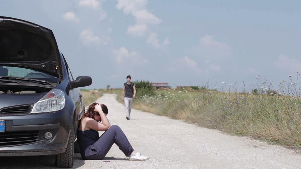 девушка сидит около поломанного автомобиля