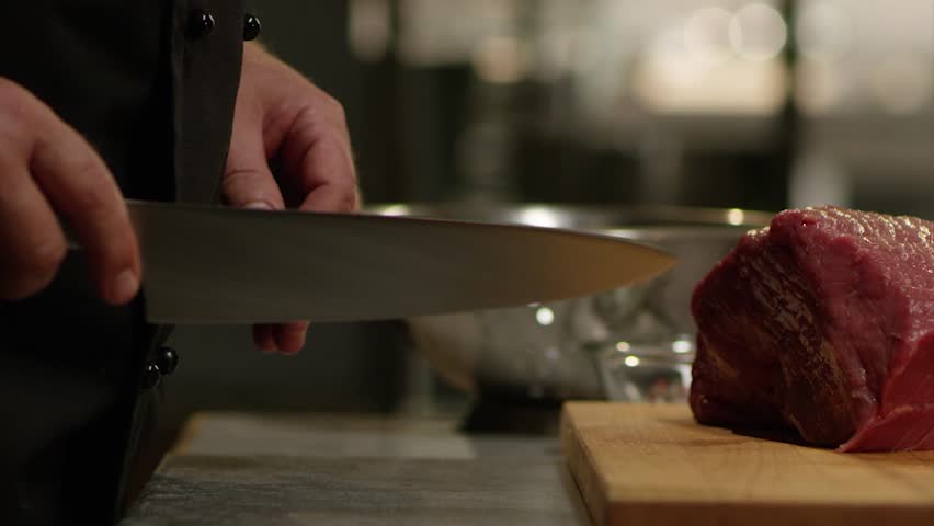 Мужчина режет мясо ножом.