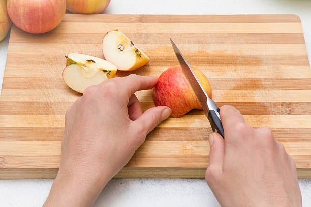 Парень режет яблоко ножом.