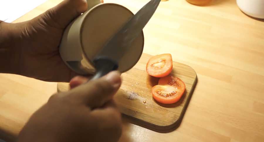 Мужчина режет помидоры кухонным ножом.