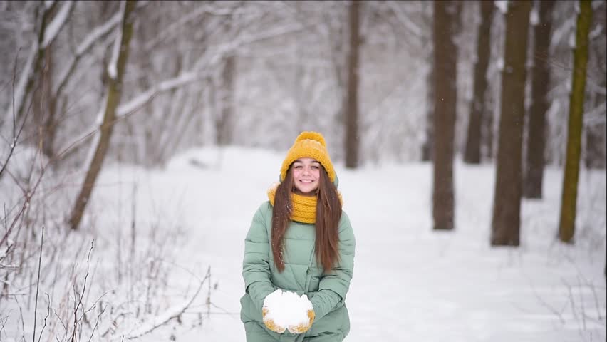 Девушка в желтой шапке посреди снега.