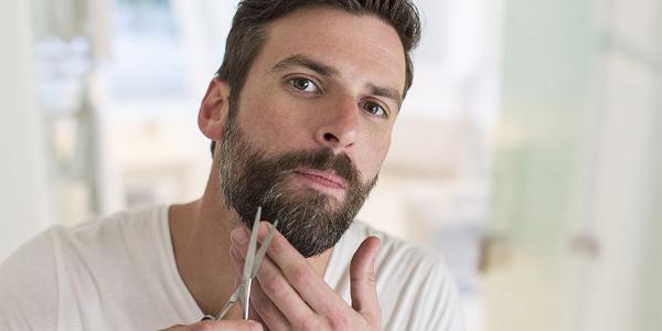 Мужчина стрижет бороду