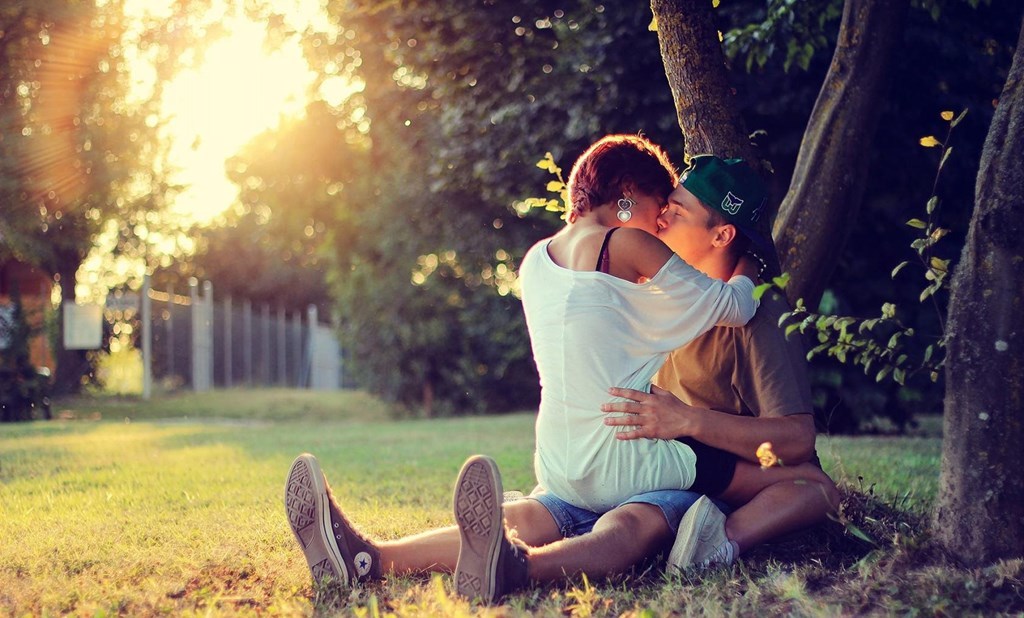 Пара целуется под деревом.