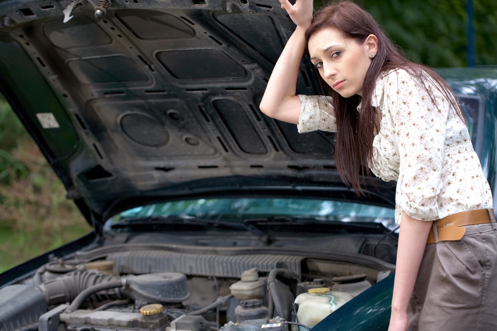 девушка стоит рядом со сломанной машиной